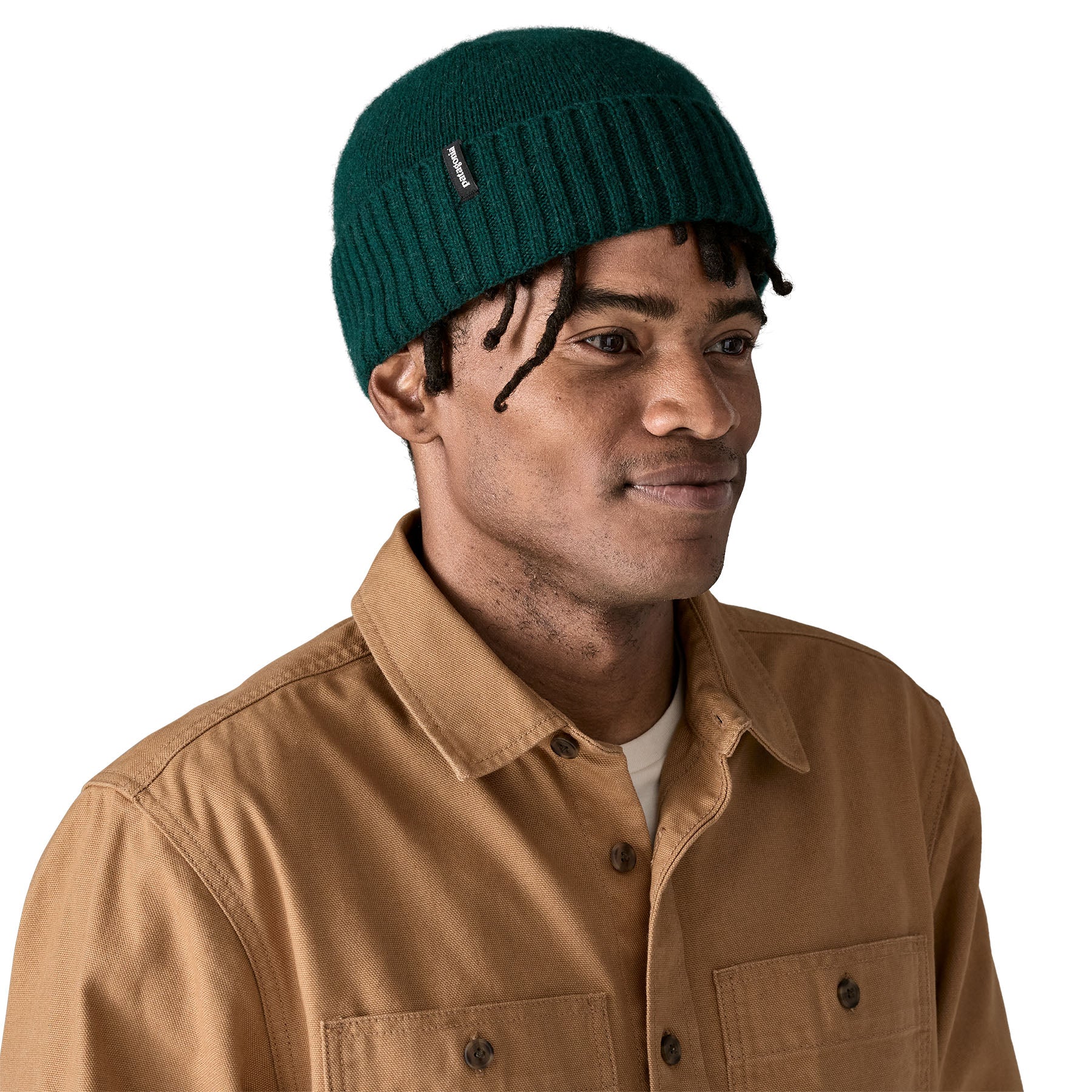 A man wearing the Patagonia adult brodeo beanie hat on cascade green. A soft knit style beanie with turn up brim and logo patch on the side available at Babipur.