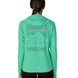 Woman wearing Patagonia women's capilene cool sun hoody in light green with peak visions graphic on the back