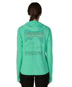 Woman wearing Patagonia women's capilene cool sun hoody in light green with peak visions graphic on the back