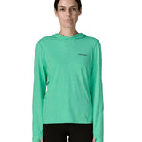 Woman wearing Patagonia's women's capilene cool sun hoody in light green with small brand logo on chest