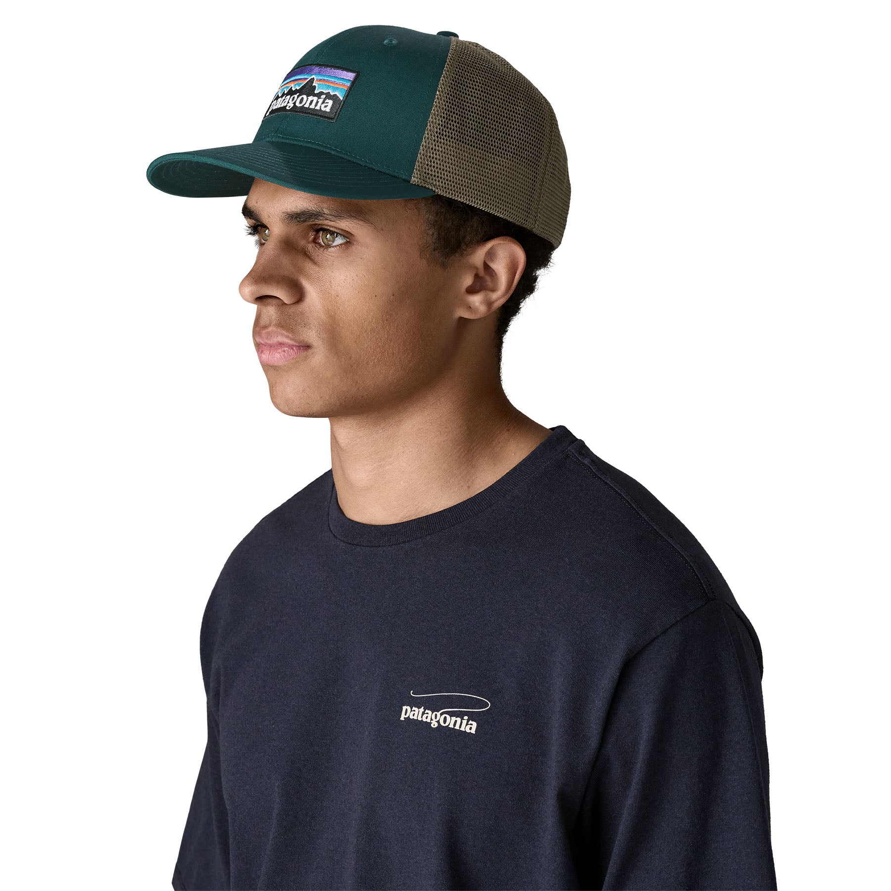 A man wearing the Patagonia adult cascade green hat. A trucker style cap with a mesh back and logo embroidery on the front panel available at Babipur.