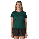 A woman wearing the Patagonia cascade green short sleeve shirt showing the brand name printed in black on the chest. 