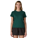 A woman wearing the Patagonia cascade green short sleeve shirt showing the brand name printed in black on the chest. 