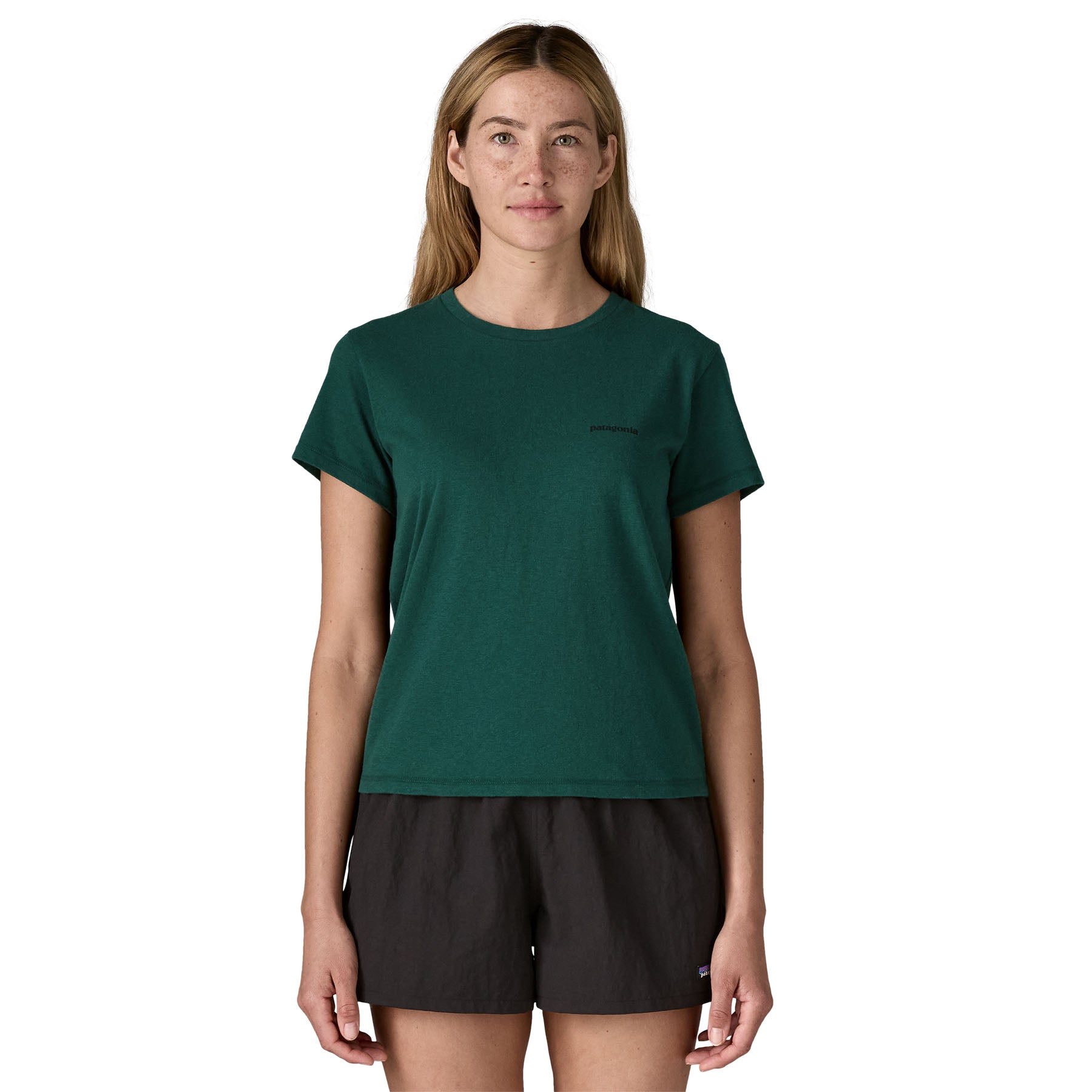 A woman wearing the Patagonia cascade green short sleeve shirt showing the brand name printed in black on the chest. 