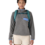 Patagonia turquoise 26L day refugio backpack worn by an adult shoulder straps and clip detail