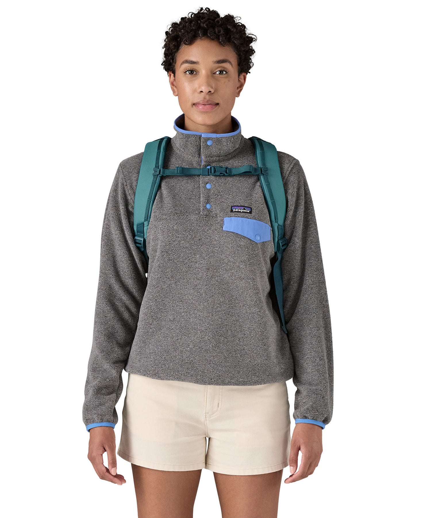 Patagonia turquoise 26L day refugio backpack worn by an adult shoulder straps and clip detail