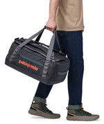 Patagonia 40 litres duffel bag in a dark navy blue colour held by an adult.