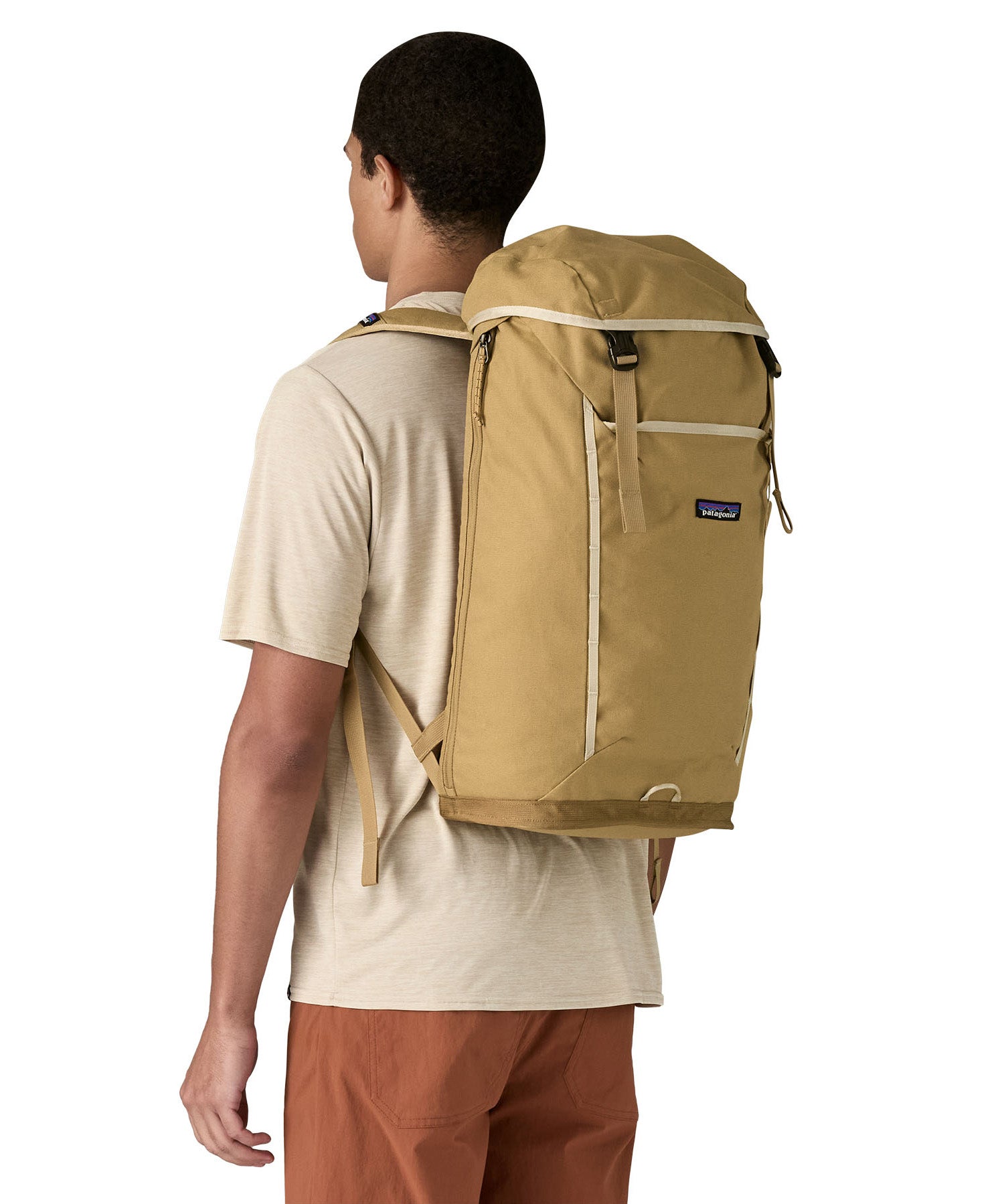 Patagonia lid fieldsmith lid backpack in classic tan worn by an adult on the back. Features the brand logo in the middle of the front panel and a contrast tan trim detail