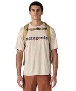 Patagonia lid fieldsmith lid backpack in classic tan worn by an adult on the back. Showing the shoulder straps detail with buckle fastening. 