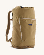 Patagonia fieldsmith roll top backpack in classic tan with zipped compartments and small blag logo tag on front.
