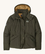 Patagonia downdrift jacket in pine green colour on a cream background.