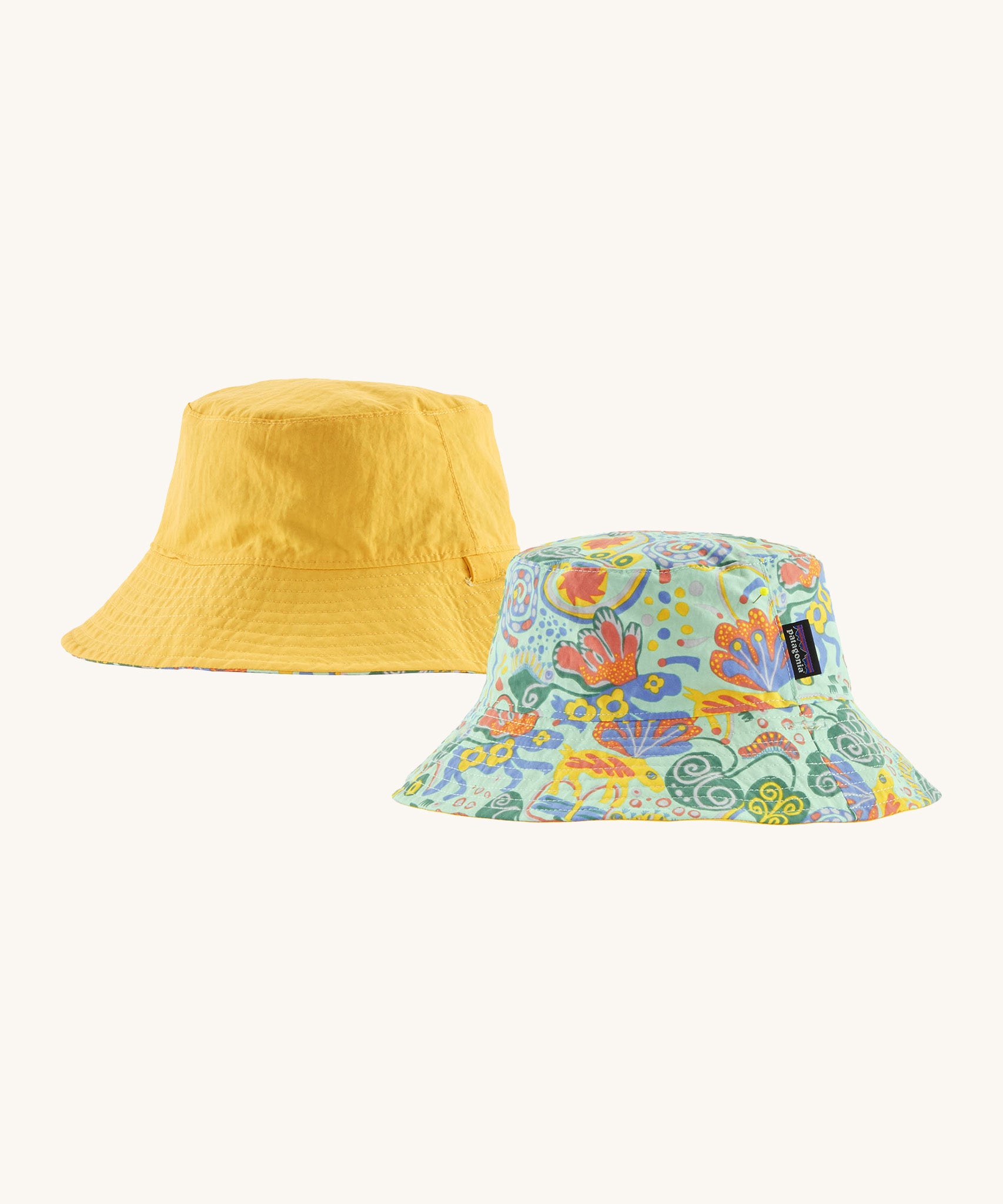 Patagonia kids bucket hat in a pastel yellow colour, green colour and multicoloured pattern design on a cream background.