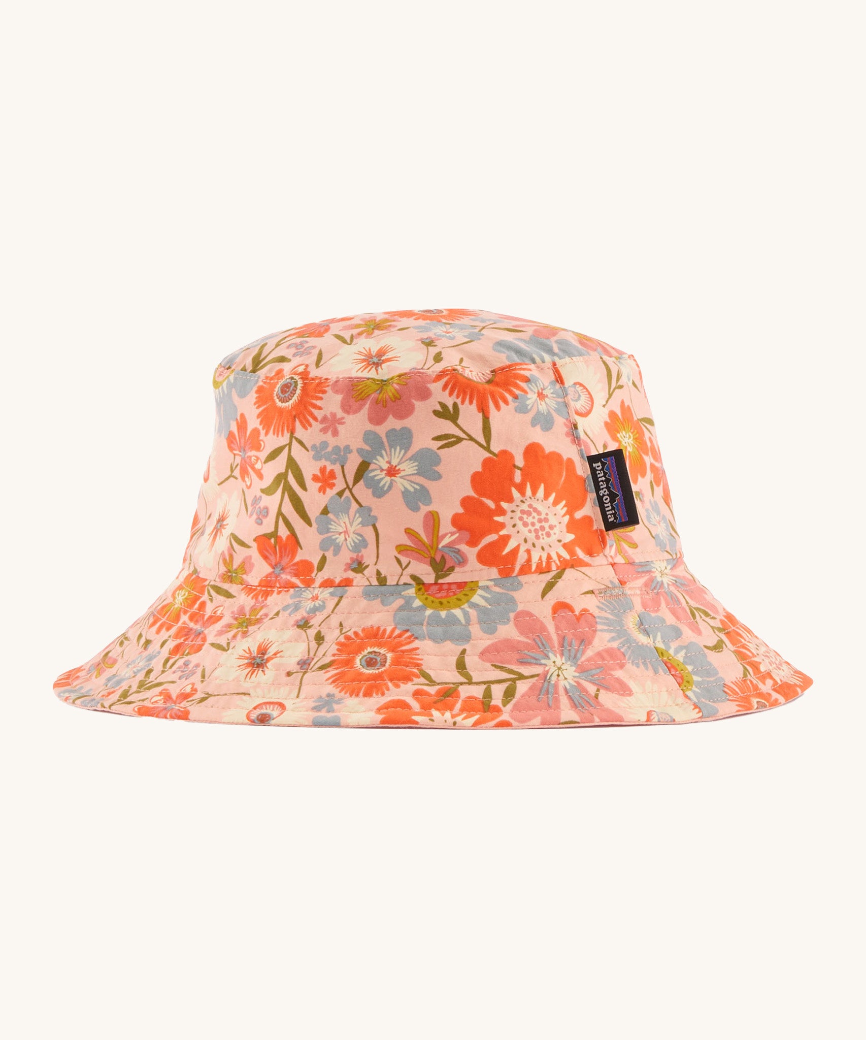 Patagonia kids bucket hat in multicoloured pink flower pattern design on a cream background.
