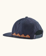Back of Patagonia kid's funhoggers hat in navy with orange trailtreck pattern around the edge showing size adjustment strap