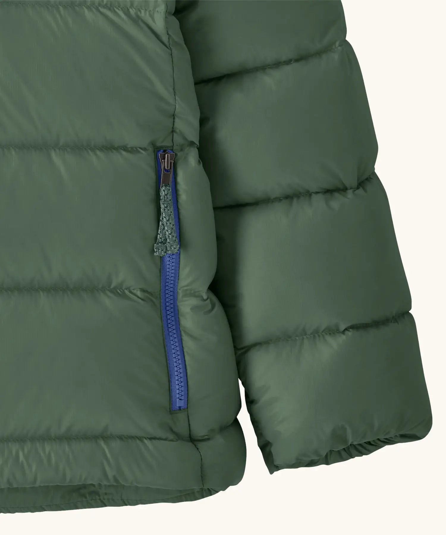 Close up of the zipped handwarmer pockets on the Patagonia kids hi-loft down sweater hoody windproof jacket in canopy green.