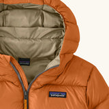 Close up of the muted yellow lined hood on the Patagonia kids hi-loft down sweater hoody windproof jacket in marigold orange.