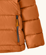 Close up of zipped handwarmer hand pockets on the Patagonia kids hi-loft down sweater hoody windproof jacket in marigold orange.