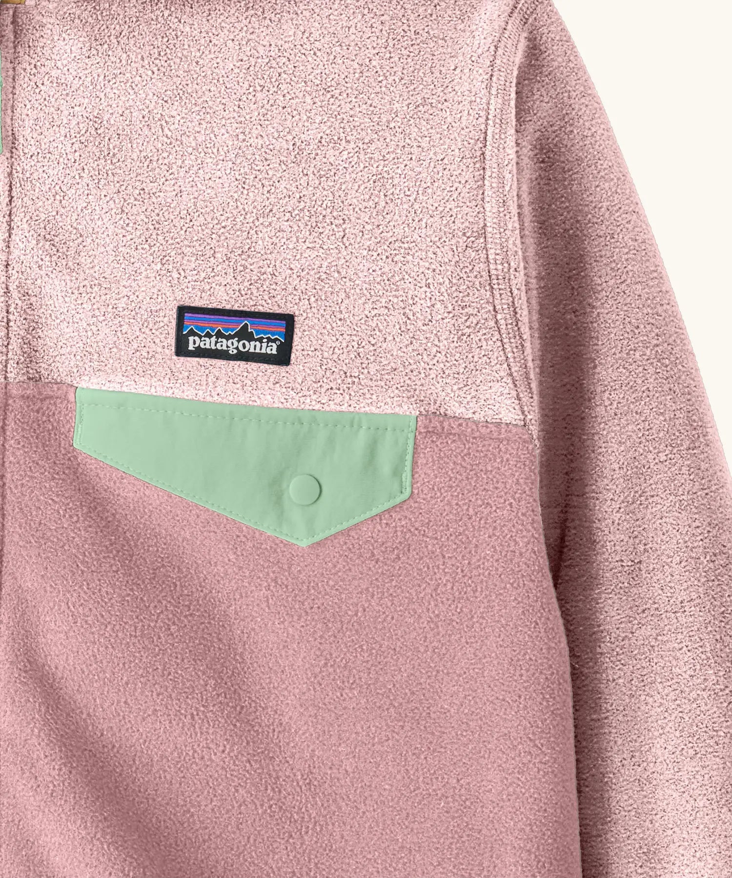 Close up of chest pocket on Patagonia kid's micro-d snap-t hooded jacket in purple and pink showing light green flap