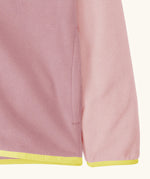 Close up of side pocket on Patagonia kid's micro-d snap-t hooded jacket in purple and pink showing light yellow trim on hem and cuff