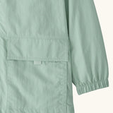 Close up of Patagonia kid's outdoor everyday hooded jacket in light green  showing front velcro pocket and elasticated cuff 