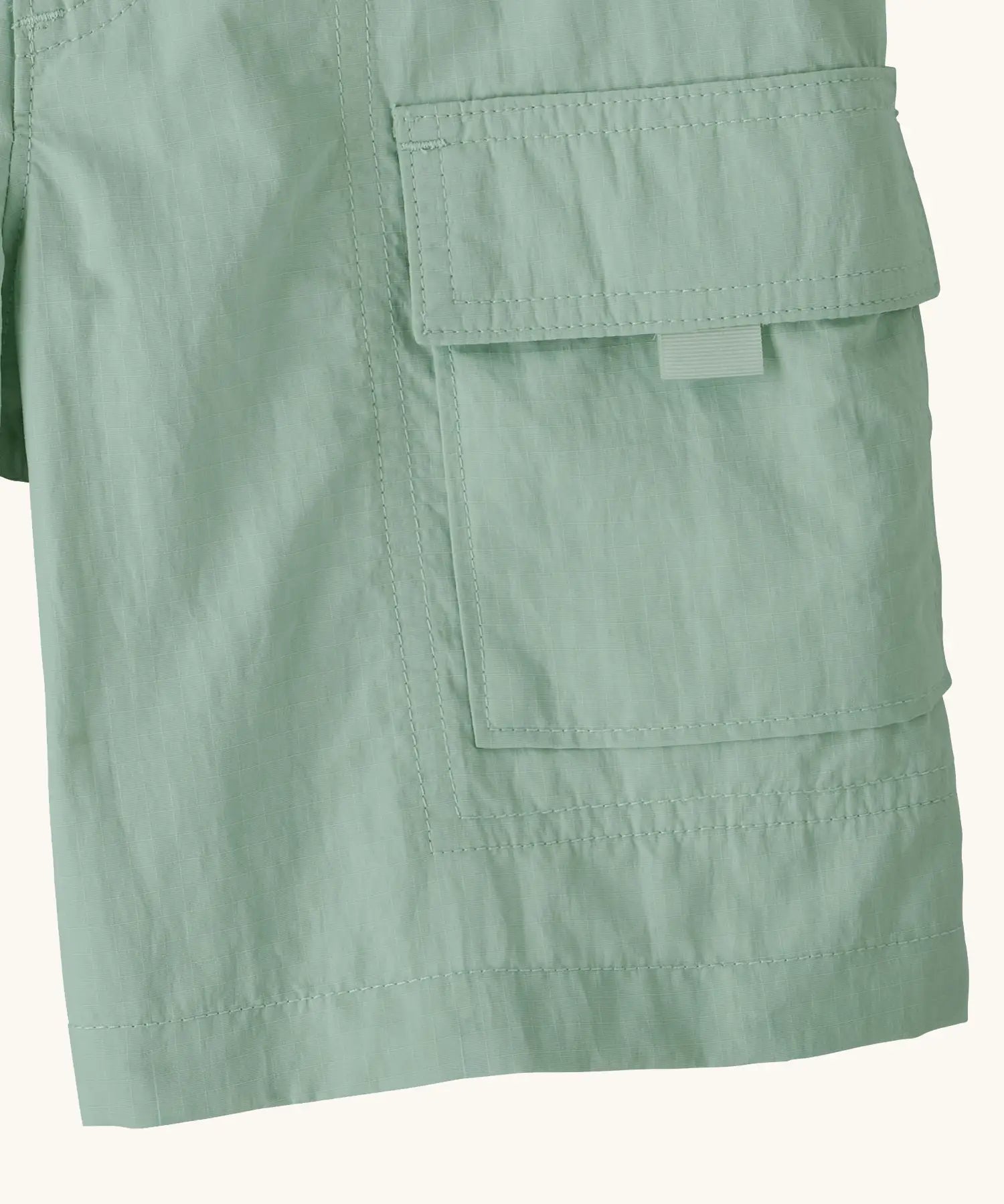 Close up of Patagonia kid's outdoor everyday 6 inch shorts in  light green showing side velcro pocket
