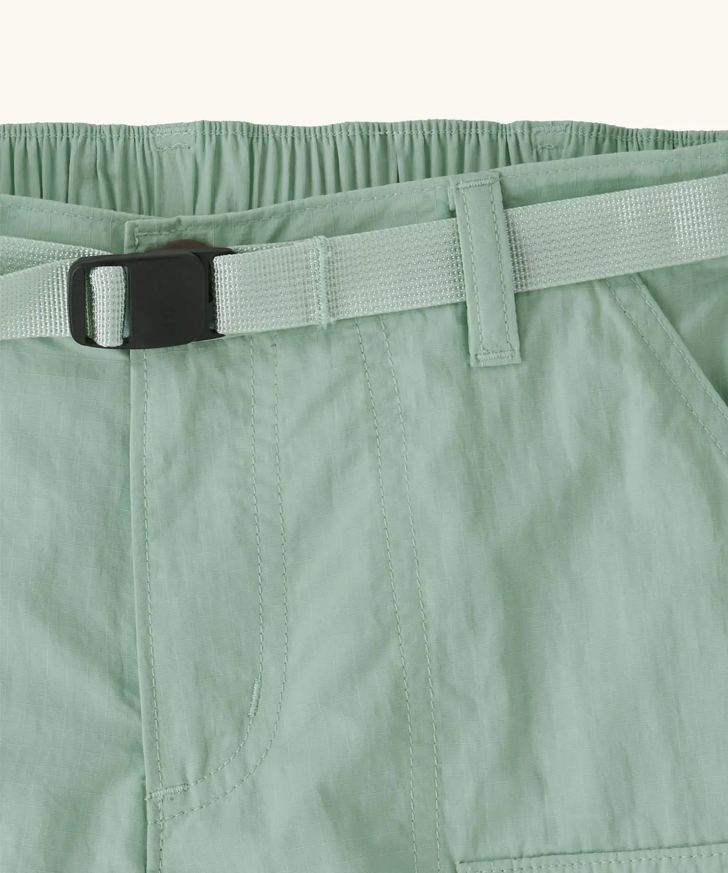 Close up of Patagonia kid's outdoor everyday 6 inch shorts in  light green showing quick release buckle belt.