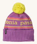 Patagonia kids powder town beanie in park stripe/brisk purple. A thick beanie with the brand name in yellow through the middle on bright purple organic fabric. Features a bright yellow pom pom on top.