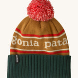 Patagonia Kids  Powder Town Beanie in park stripe talon gold colour. A gold beanie with a green turn up brim. Features a red and white pompom on top and the brand name across the middle in white