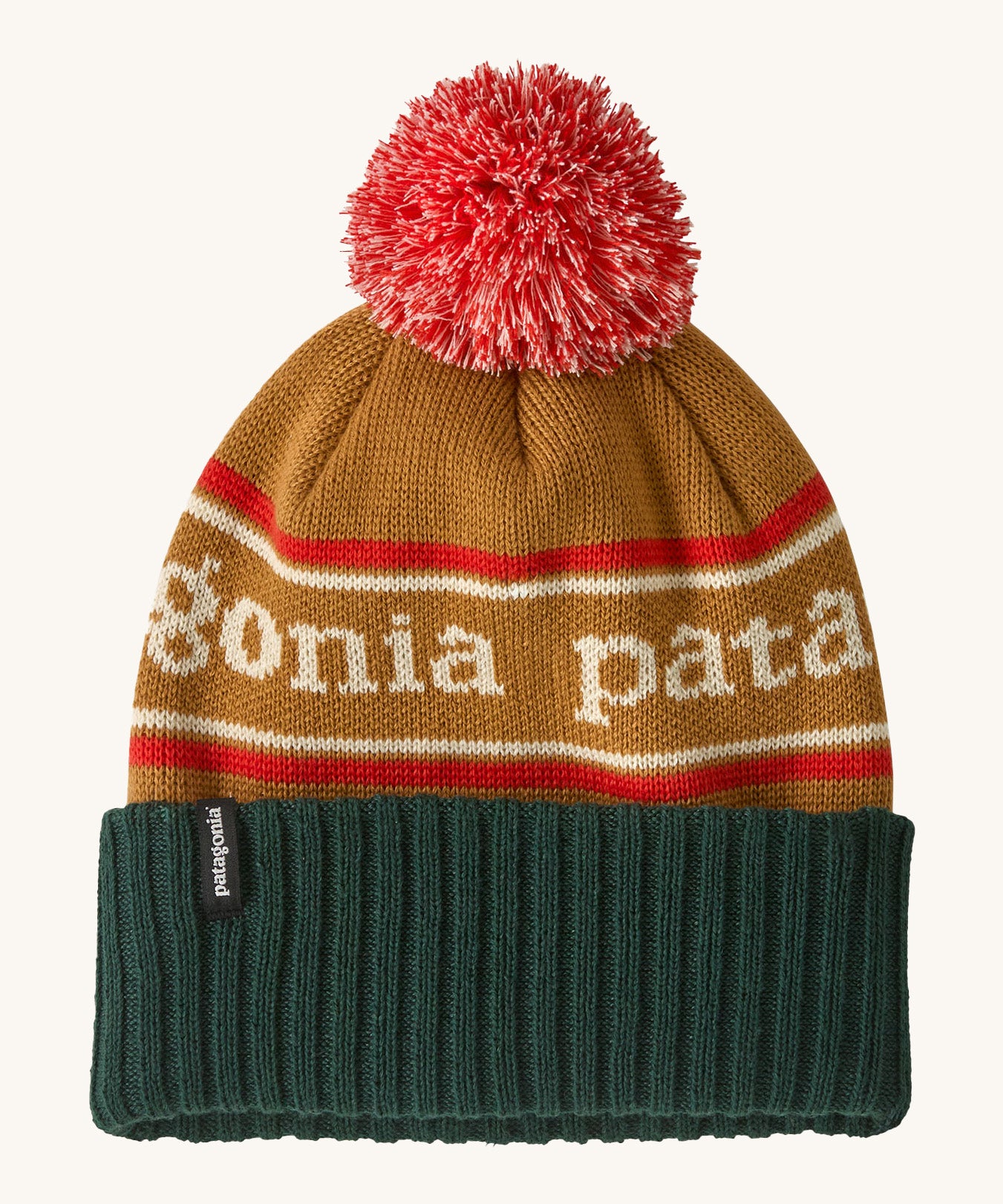 Patagonia Kids  Powder Town Beanie in park stripe talon gold colour. A gold beanie with a green turn up brim. Features a red and white pompom on top and the brand name across the middle in white