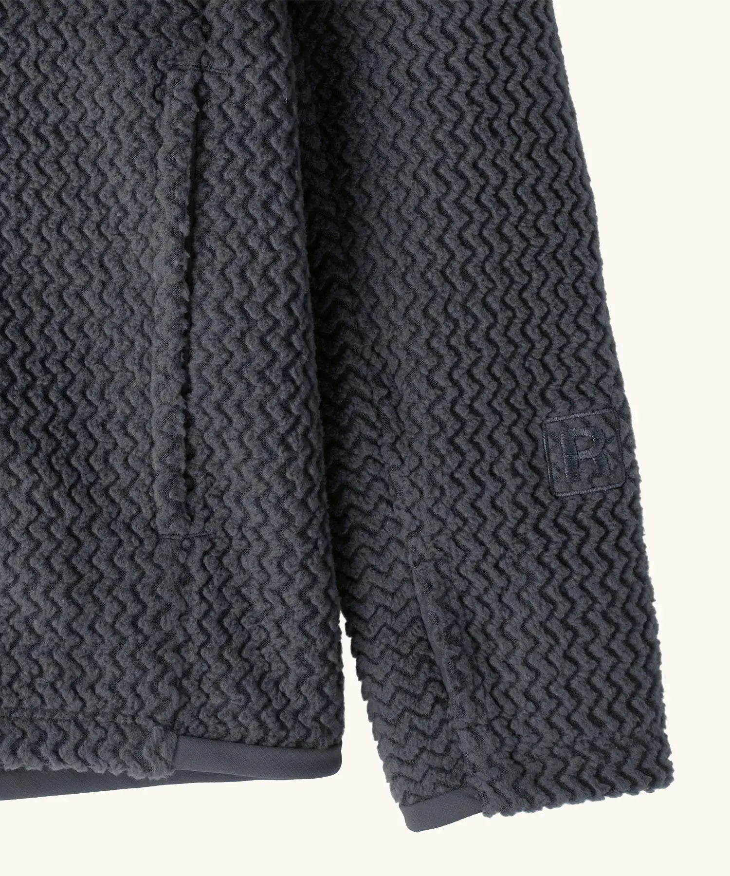 Close up of the side pockets and thumb holes on Patagonia high performance kids R1 air hoody in navy blue. 