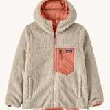 Patagonia Kids Reversible Ready Freddy Hoody in the Moment Pink colour way. The kids coat is shown with the off white, cream coloured high pile fleece on the outside.  We're proud stockists of Patagonia here at Babipur.