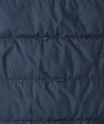 Close up of water droplets pooling on material of the patagonia kids reversible ready freddy hoody water resistant jacket in new navy.