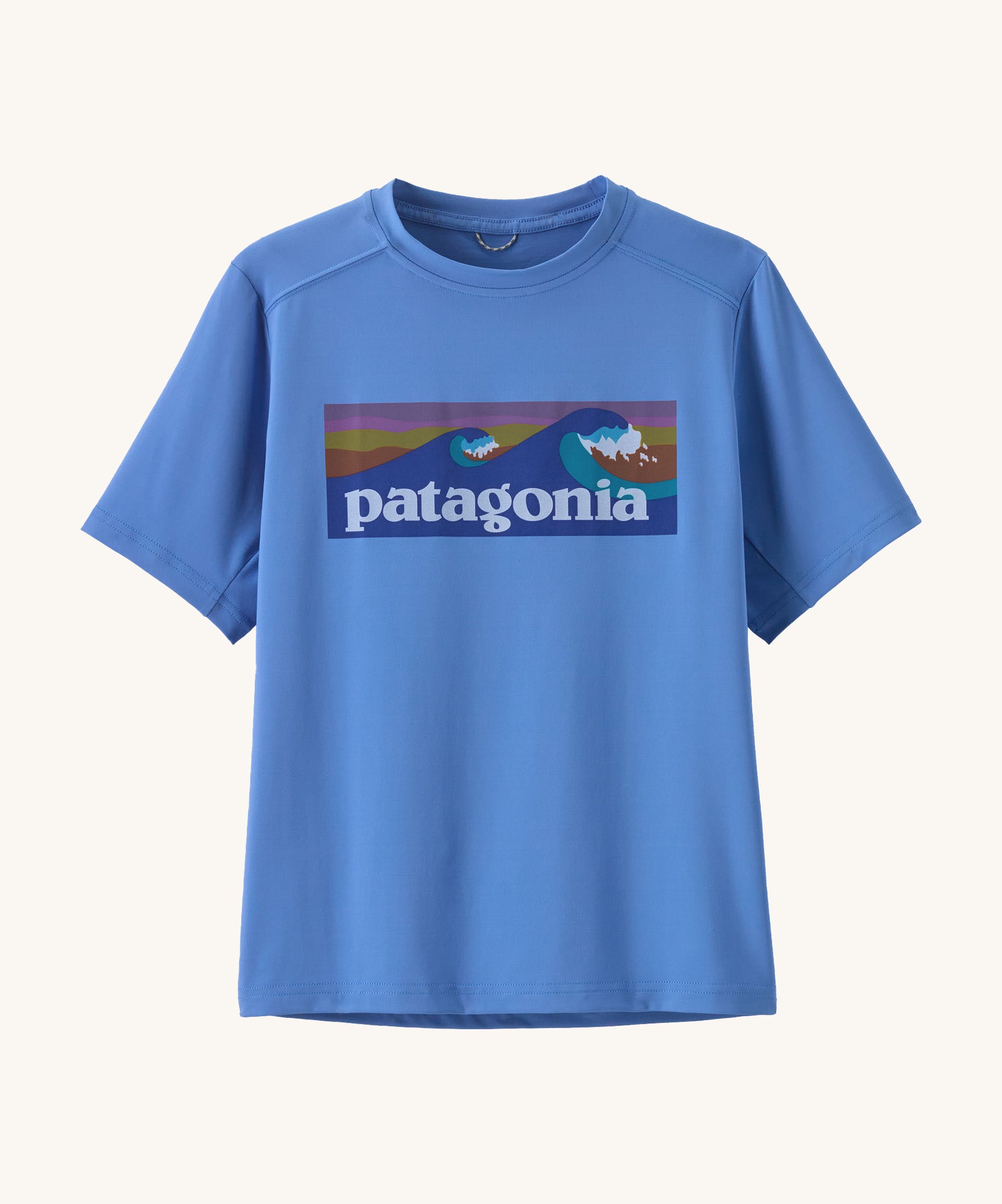 Patagonia kids short sleeve cap tshirt in a light blue colour with logo on a cream background.