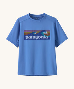 Patagonia kids short sleeve cap tshirt in a light blue colour with logo on a cream background.