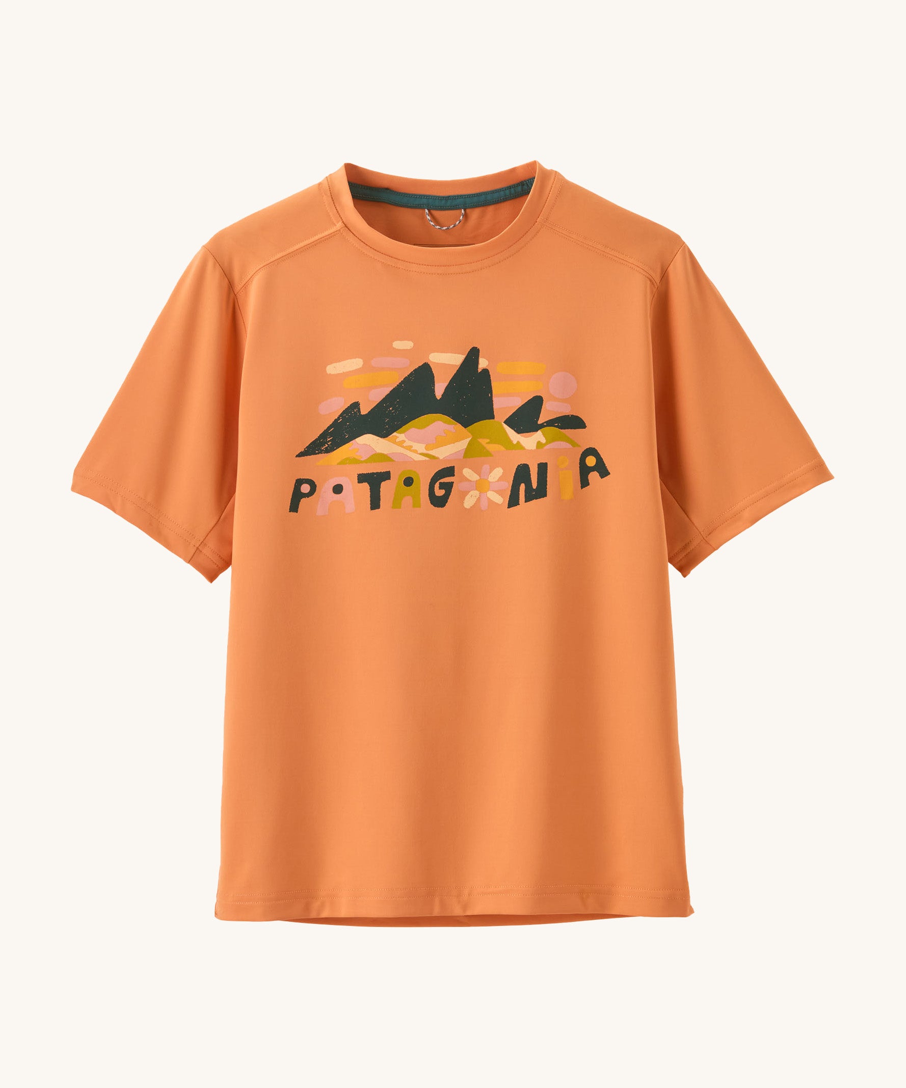 Patagonia kids short sleeve cap tshirt in a peach colour with logo on a cream background.