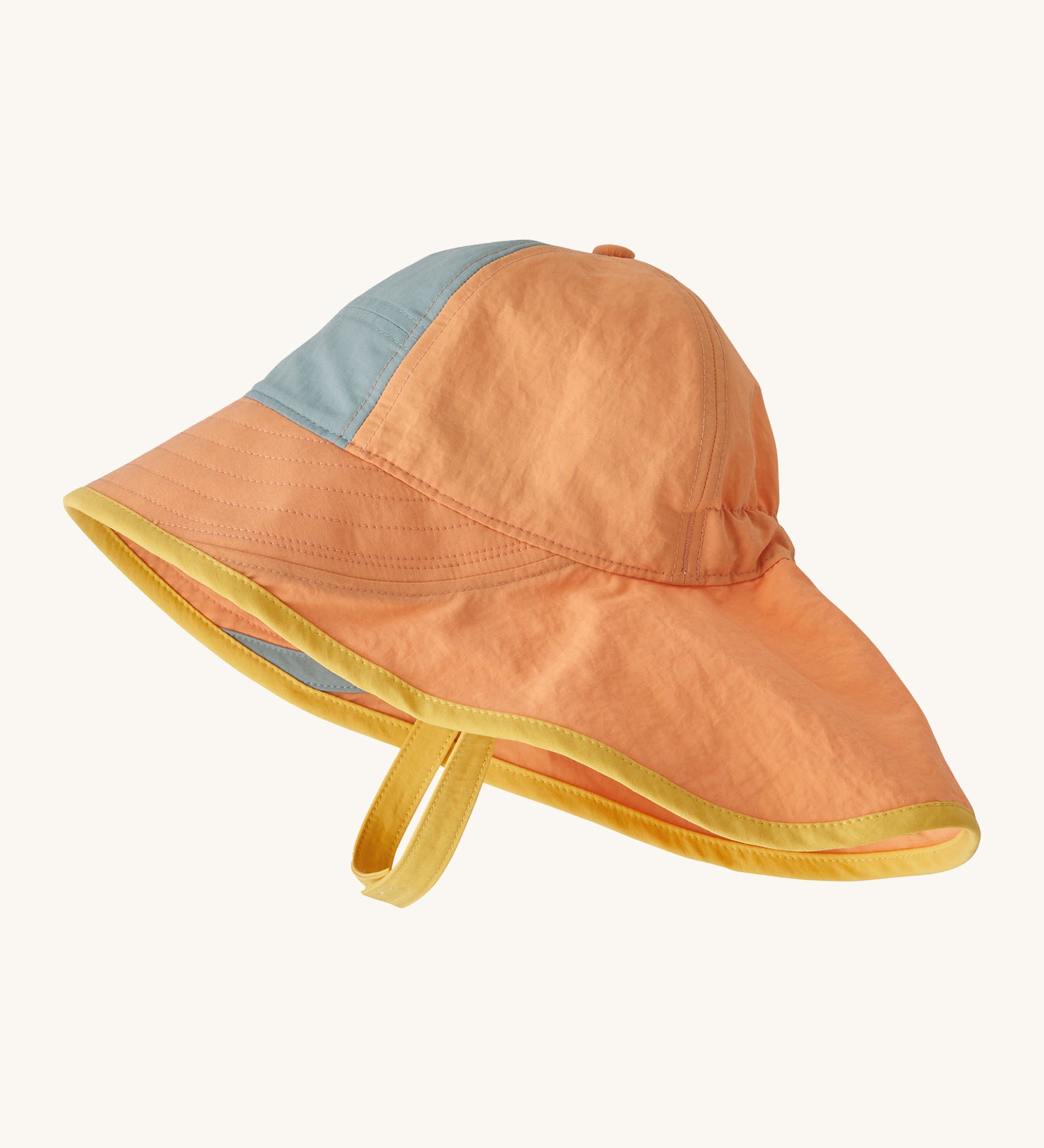 Patagonia kids sun har in a peach colour on a cream background