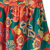 Close up of the lightly pleated skirt on the Patagonia kid's tidal threads sleeveless dress in hot ember orange with a leafy themed tropiclimb print all over. 