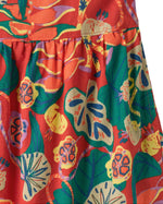 Close up of the lightly pleated skirt on the Patagonia kid's tidal threads sleeveless dress in hot ember orange with a leafy themed tropiclimb print all over. 
