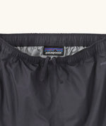 Close up of elasticated waist with inside ties on the Patagonia kids waterproof torrentshell 3L rain pants in black.