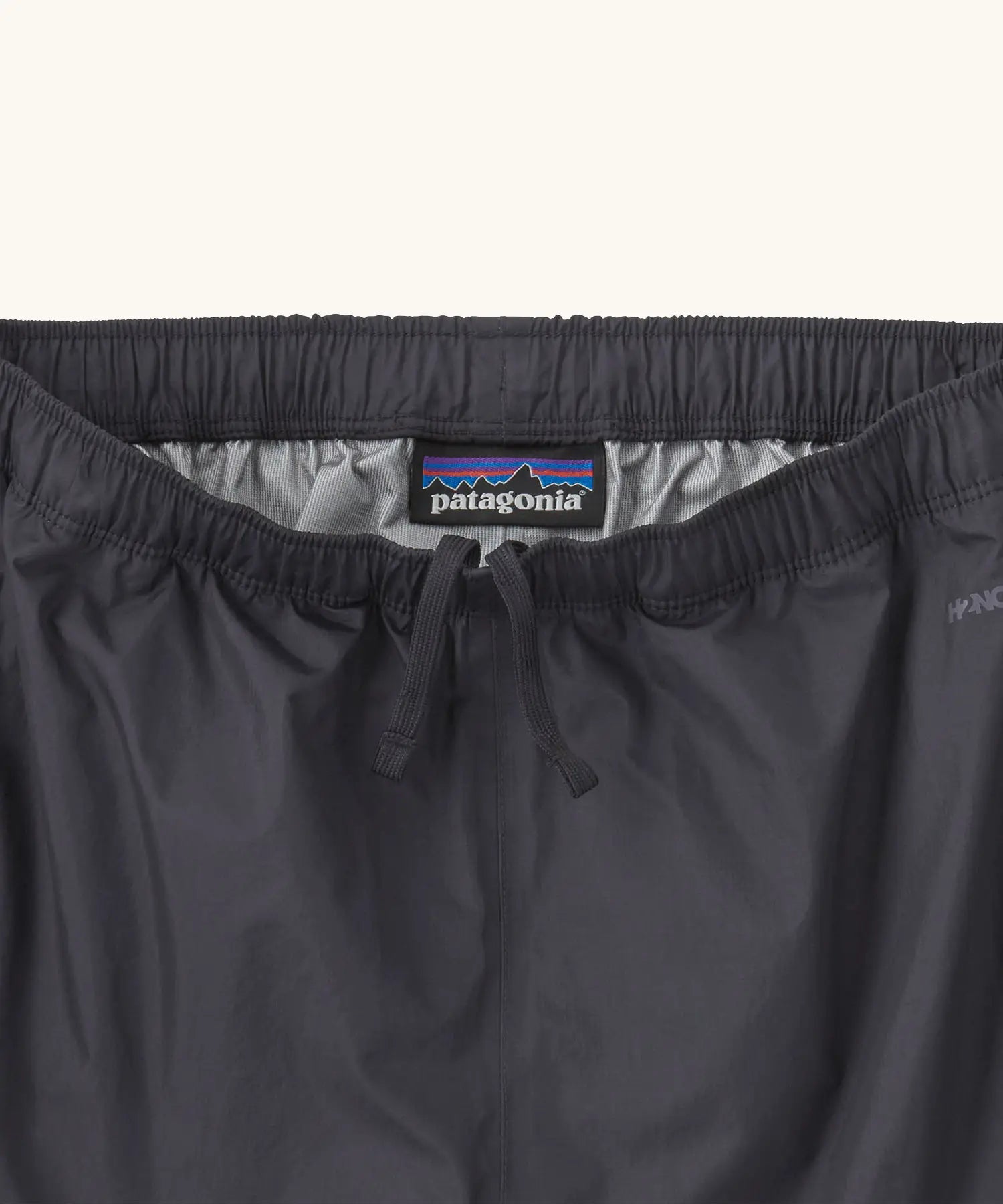 Close up of elasticated waist with inside ties on the Patagonia kids waterproof torrentshell 3L rain pants in black.