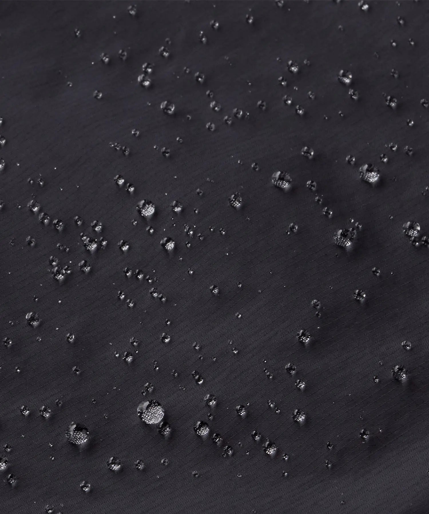 Close up of water droplets formed on the Patagonia kids waterproof torrentshell 3L rain pants in black.