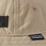 A close up of a Patagonia Kid's Trim Brim Hat in a beige colour showing the water repellent outer. 