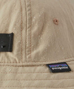 A close up of a Patagonia Kid's Trim Brim Hat in a beige colour showing the water repellent outer. 