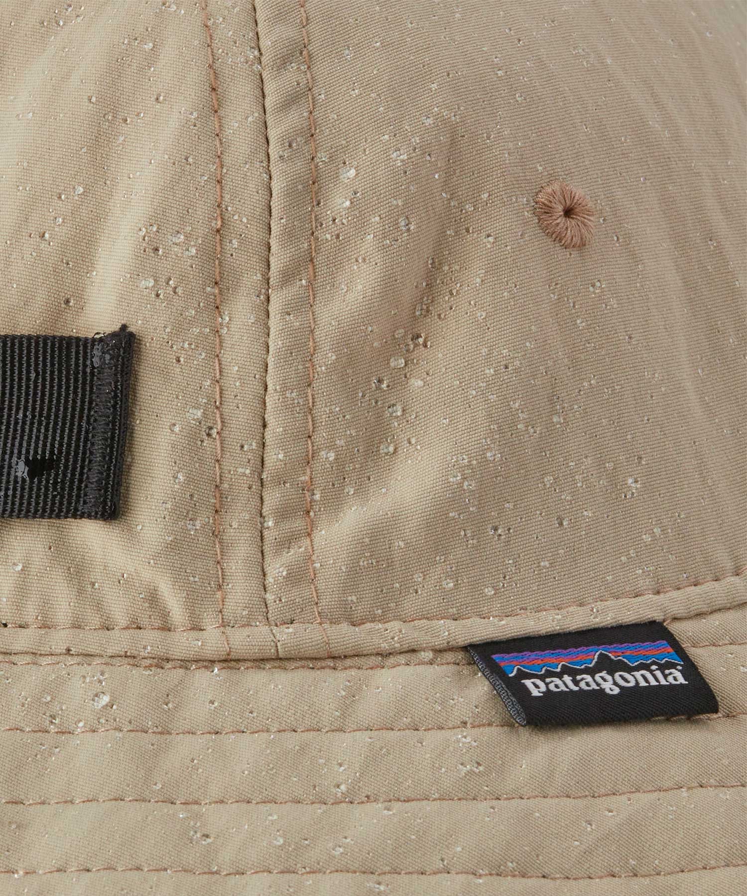 A close up of a Patagonia Kid's Trim Brim Hat in a beige colour showing the water repellent outer. 