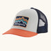 Patagonia kids trucker hat with white front, coral bill and blue mesh panel. Showing brand patch on the front