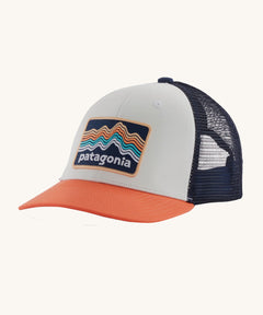 The Patagonia Kids Trucker Hat Ridge Rise Stripe / Coho Coral on a plain background. 