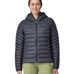 A woman wearing a Patagonia Women's Down Sweater Hoody in a Smolder Blue colour.