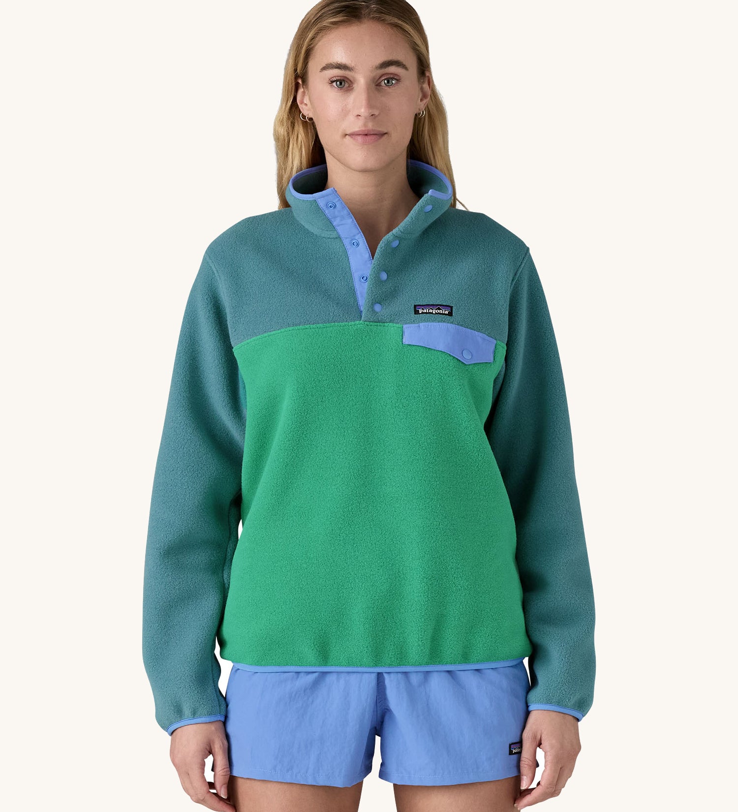 A woman wearing a Patagonia Women's Lightweight Synchilla Snap-T Fleece in a Heartleaf Green colour. 