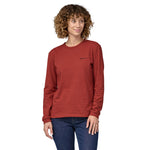 Woman wearing atagonia Long Sleeved Responsibili-Tee in red with a small Patagonia logo on the top right - the lowest carbon footprint t-shirt - made from recycled cotton and post-consumer recycled polyester.