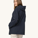 A woman wearing a Patagonia Women's Outdoor Everyday Rain Jacket in a Pitch Blue colour. The woman is facing away from the camera showing the back of the jacket. 